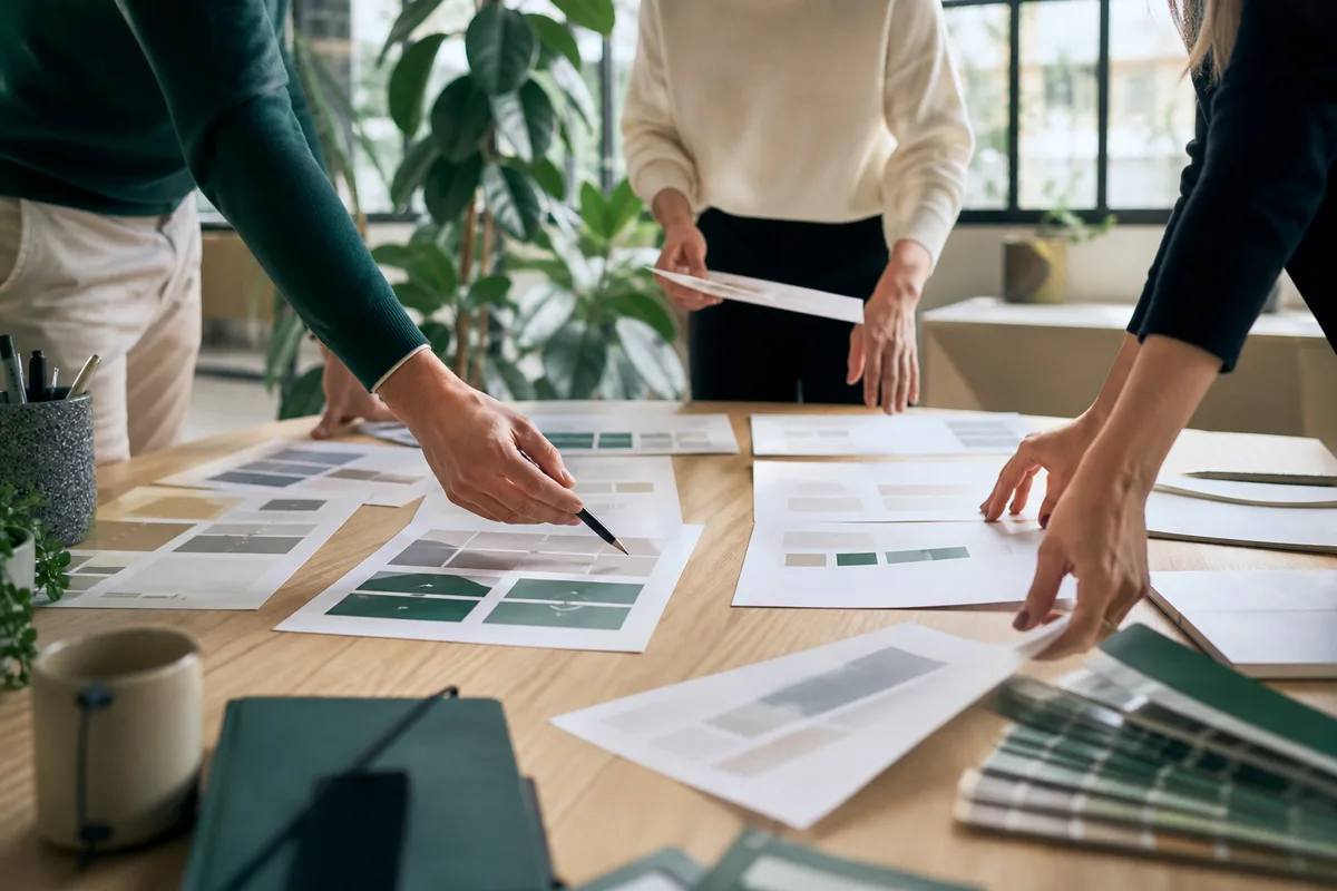 Réunion de travail autour de maquettes de site imprimées sur une table